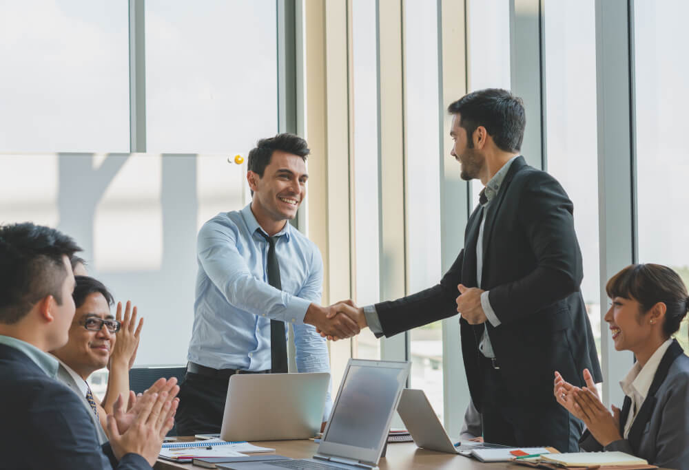 Colleagues applauding a handshake in a meeting