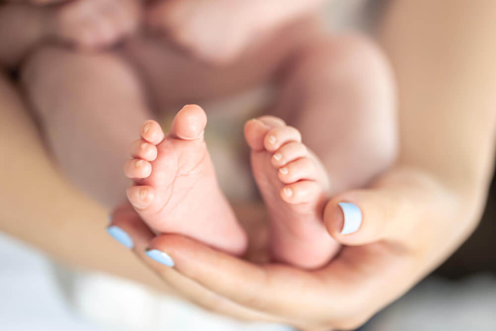 Newborn baby's feet cradled in hands