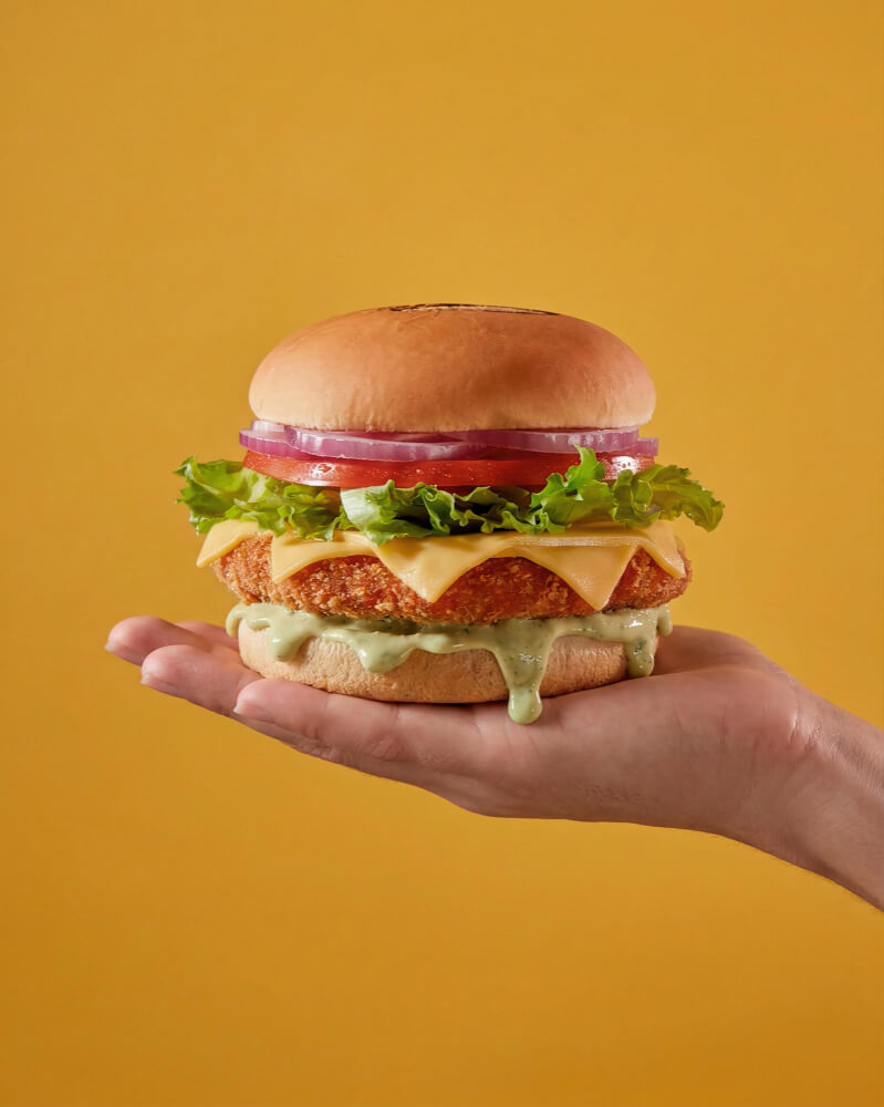Burger held up against an orange backdrop