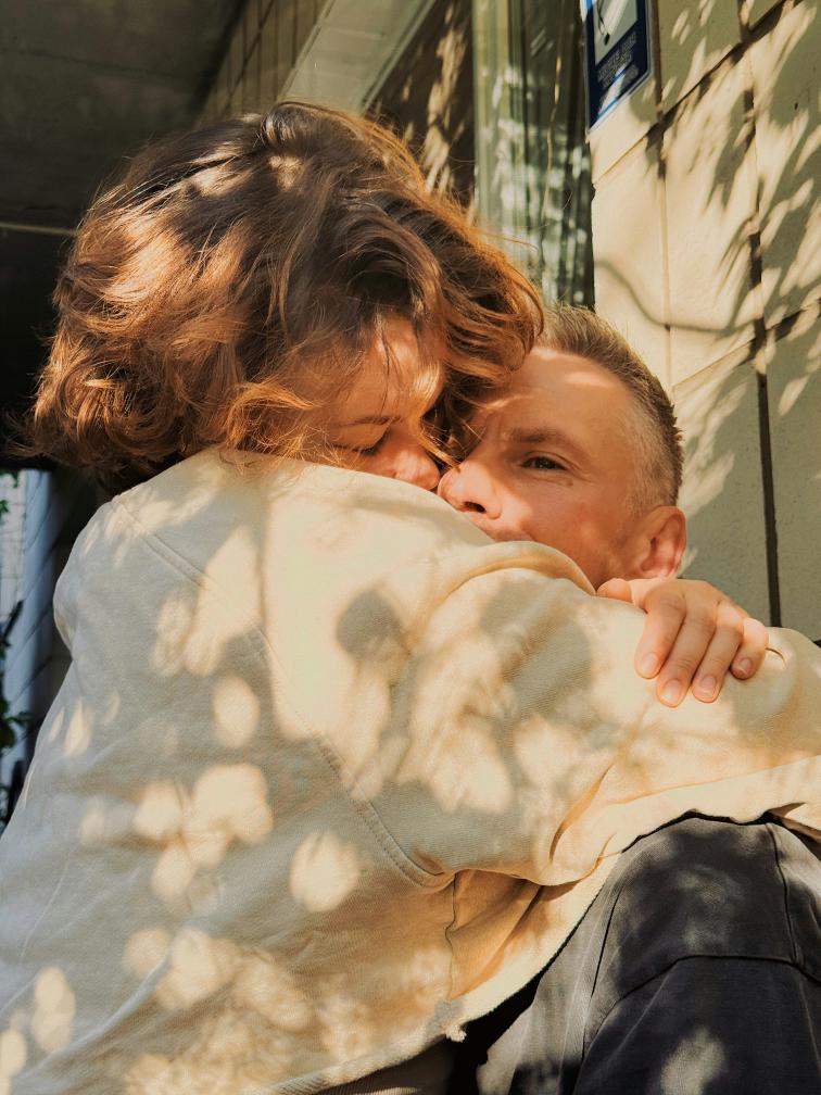 Couple embracing in warm, dappled sunlight